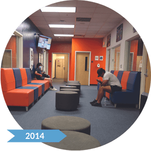 Two students sitting on blue and orange couches outside of offices