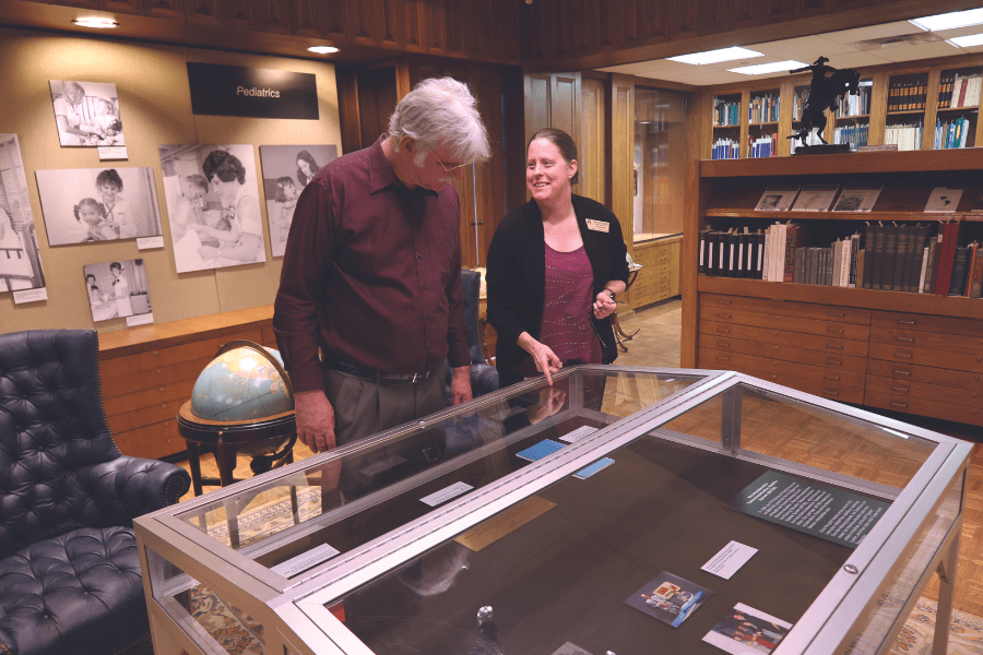 Christine Roberts pointing and showing a man the nursing exhibit display