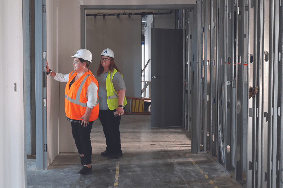 Two women in constriction outfits inside of the new Social work/smart hospital buidling